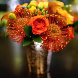 Orange floral bouquet in a metallic vase