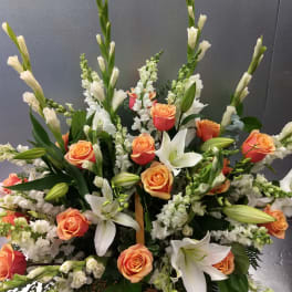 Large floral arrangement with orange roses, white lilies, and white spikes in a basket