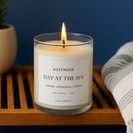 Lit soy candle in a clear glass jar on a wooden tray