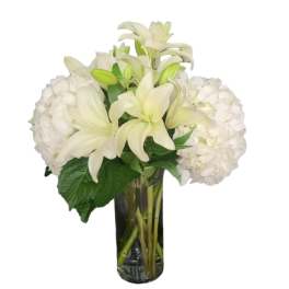 White lilies and hydrangeas arranged in a glass vase