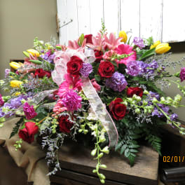 Large mixed bouquet of roses, lilies, and purple flowers with a ribbon