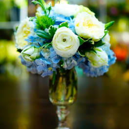 Blue and white flower arrangement in a glass goblet vase