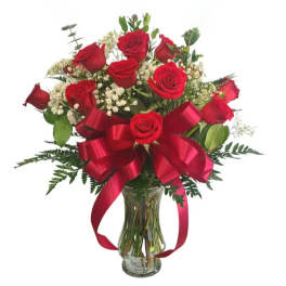 Red roses arranged in a clear glass vase with a large red ribbon