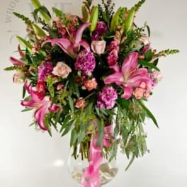 Pink lilies and roses in a clear glass vase