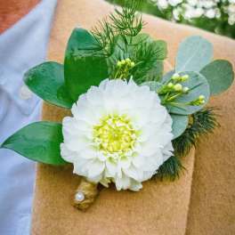 White flower boutonniere with green foliage on brown wrap