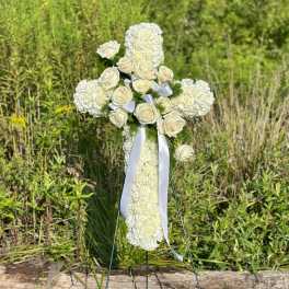 White floral cross with roses on a standing easel outdoors