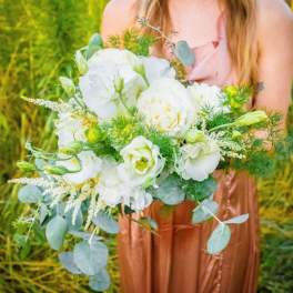 White bouquet with eucalyptus and green filler held by a woman