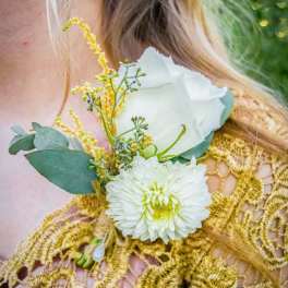 White rose and chrysanthemum corsage with yellow accents on a gold dress