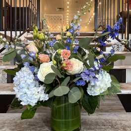 Mixed bouquet of blue and white flowers in a green glass vase