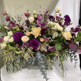 Large bouquet of purple, pink, and cream flowers with trailing greenery