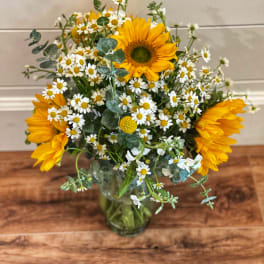 Sunflowers and white daisies arranged in a glass vase