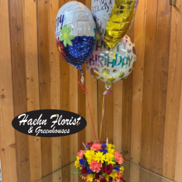 Birthday balloons above a colorful flower arrangement in a vase