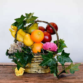Fruit basket with a pink gerbera daisy and yellow rose