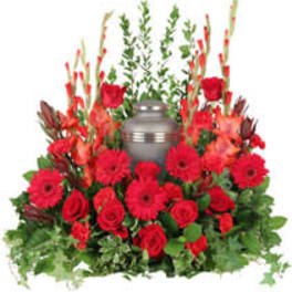 Red roses and gerbera daisies arranged around a gray urn