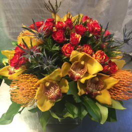 Bouquet of red roses and yellow orchids in a glass vase