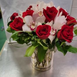 Red roses and white orchids arranged in a clear glass vase