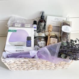 Gift basket with lavender items, candles, diffuser, chocolates, and a small bouquet
