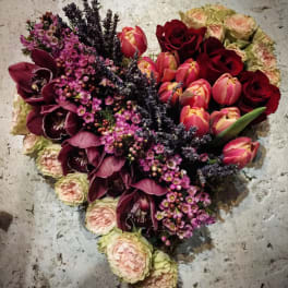 Heart-shaped bouquet of red roses, pink tulips, and purple orchids
