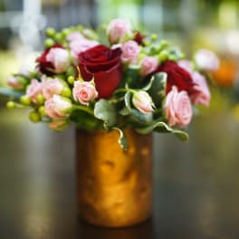 Pink and red roses arranged in a gold vase