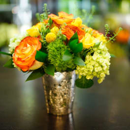 Orange and yellow roses arranged in a silver vase