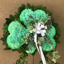 Green carnation wreath with white ribbon and dark foliage