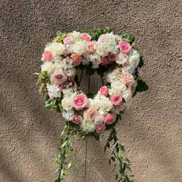 Heart-shaped floral wreath of pink and white roses on a stand