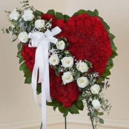 Heart-shaped red floral tribute with white roses and a white ribbon