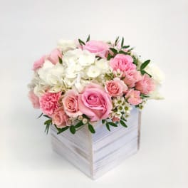 Pink and white roses with hydrangeas in a white wooden box