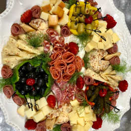 Charcuterie platter with cheeses, olives, strawberries, and rolled meats on a white tray