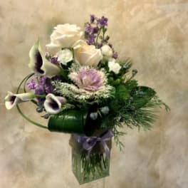 Bouquet of white roses and purple calla lilies in a glass vase