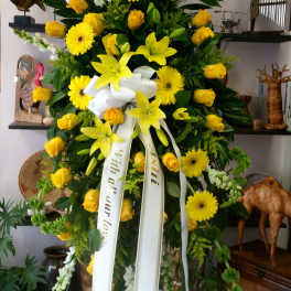 Large yellow floral standing spray with ribbon on an easel