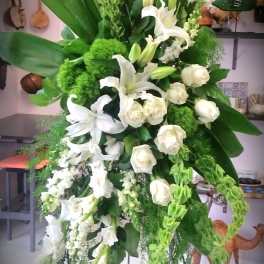 Tall white floral standing spray with lilies and roses on a metal easel