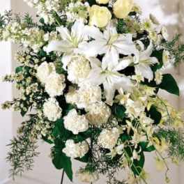White lilies and pale yellow roses in a standing floral spray