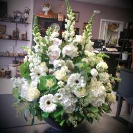 Large white floral arrangement in a black bowl vase