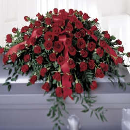 Large red rose casket spray with ribbon on a gray casket