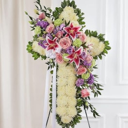 Standing floral cross with pink roses and lilies on a white easel