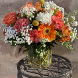 Mixed bouquet of orange, pink, and white flowers in a glass vase