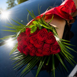 Bouquet of red roses wrapped in brown paper with red ribbon