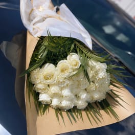 Bouquet of white roses wrapped in brown paper with white tissue