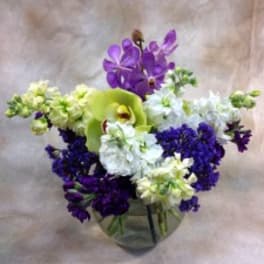 Purple and white floral arrangement in a glass vase