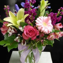 Mixed bouquet with pink roses, lilies, and a pink daisy in a glass vase
