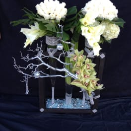 Two white floral arrangements in tall black vases with silver accents
