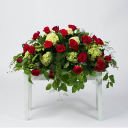 Red roses and pale green hydrangeas arranged on a white table