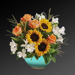 Sunflowers, peach roses, and white alstroemeria in a turquoise bowl vase