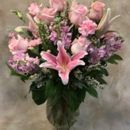 Pink roses and lilies arranged in a glass vase