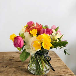 Mixed bouquet of pink, yellow, and white flowers in a glass vase