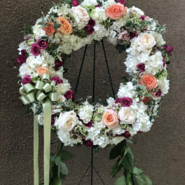 Floral wreath with white, peach, and magenta roses on a stand