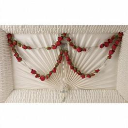 White coffin with red rose garlands arranged across the lid