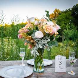 Pastel floral centerpiece in a glass vase on a wedding table