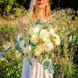 Bride holding a large bouquet of white roses and greenery